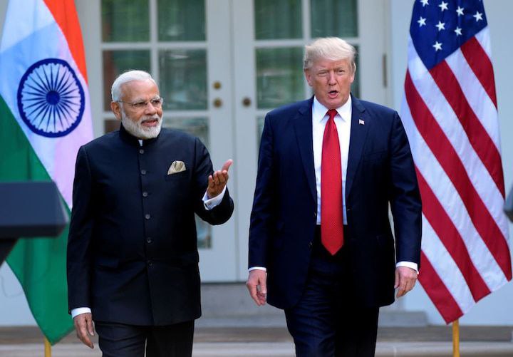 नरेंद्र मोदी और डोनाल्ड ट्रंप के बीच सौहार्दपूर्ण मुलाकात, पृष्ठभूमि में भारत और अमेरिका के राष्ट्रीय ध्वज

