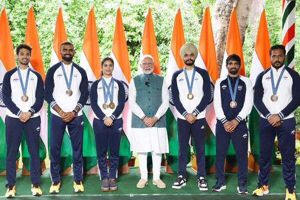 2030 Commonwealth Games: भारत की बोली और तैयारी 3 “Indian athletes with medals posing with Prime Minister in front of national flags”